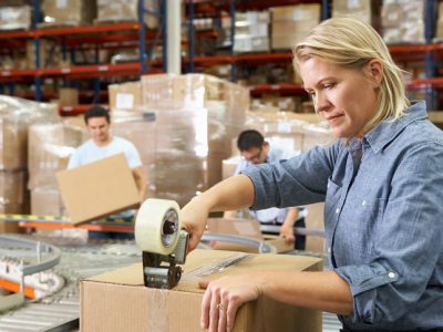 Workers In Distribution Warehouse Packing Boxes